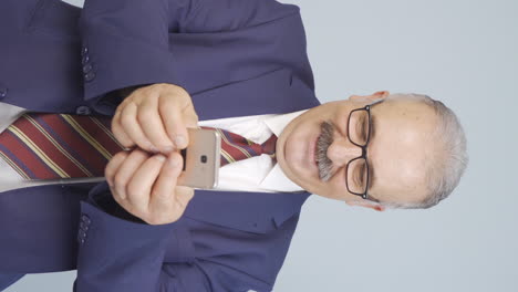 Vertical-video-of-Old-businessman-texting-on-the-phone.-Happy-emoticon.